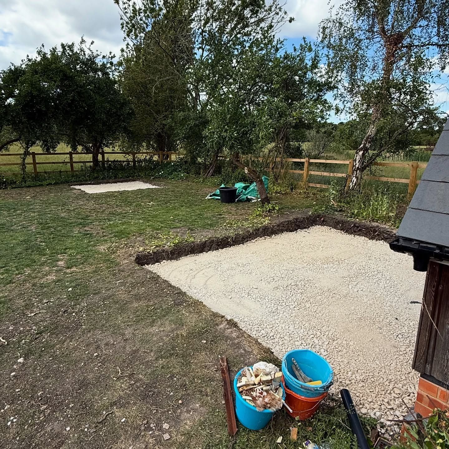 A bucket of dirt is sitting in the grass next to a brick building.