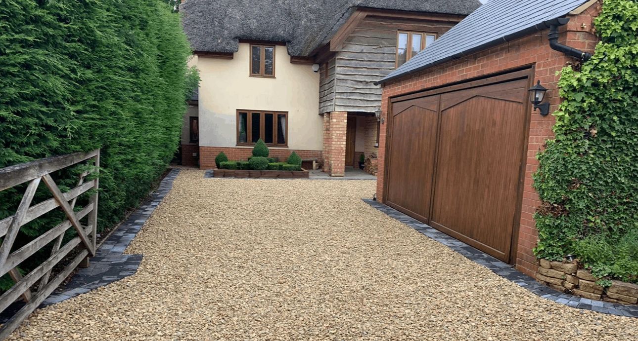 A large house with a garage and gravel driveway leading to it.