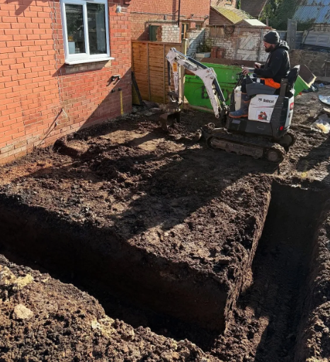 A man is driving a small excavator in the dirt