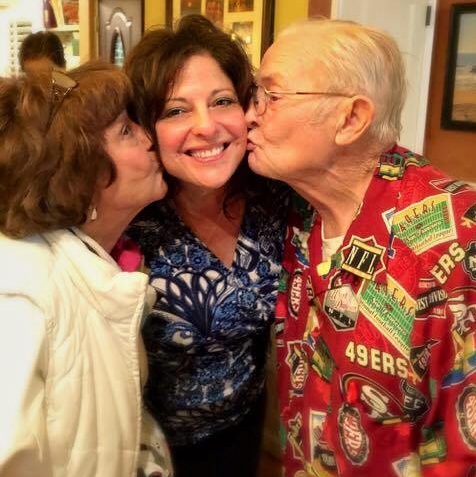 A man in a 49ers shirt kisses a woman on the cheek