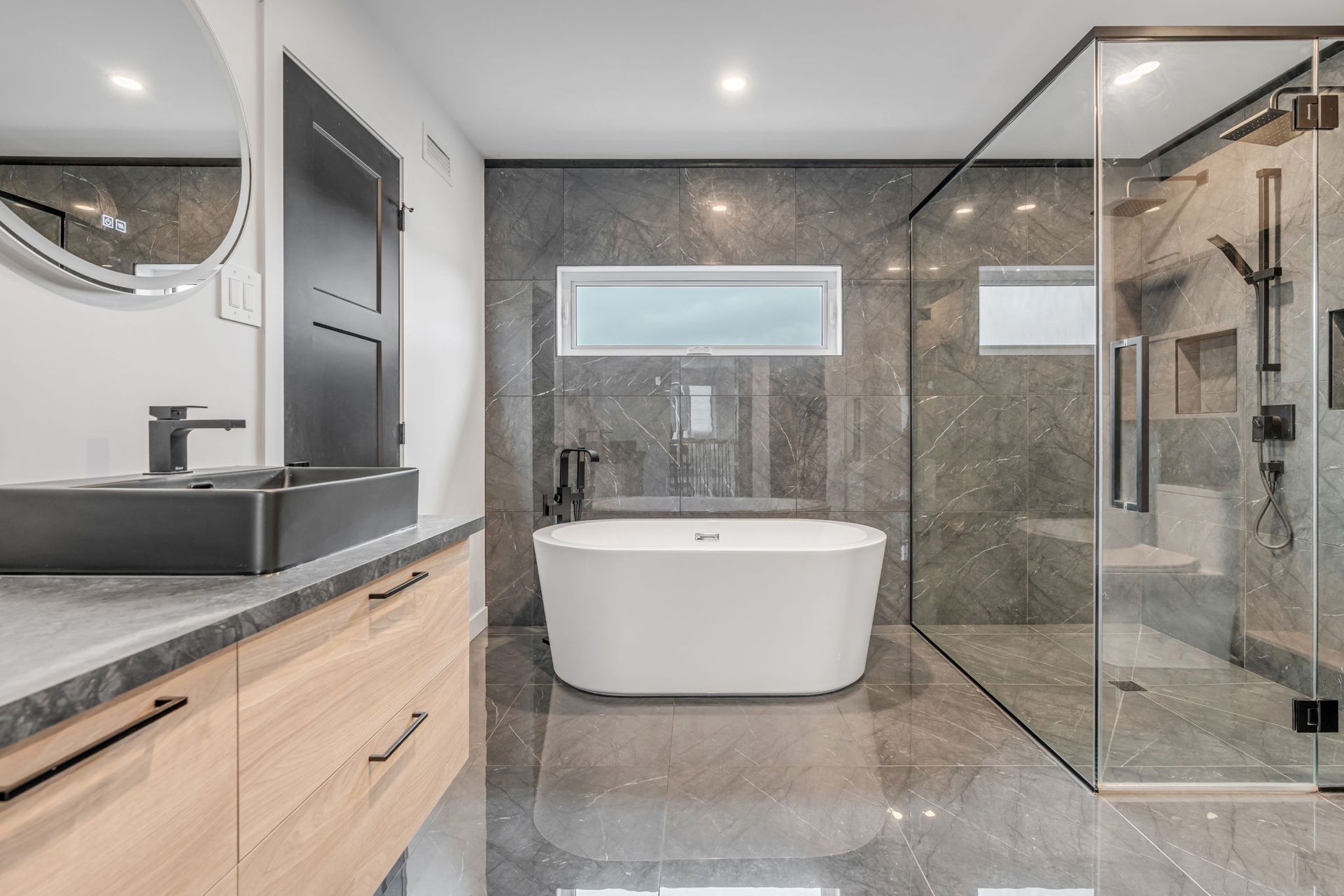 Salle de bains moderne avec carrelage en marbre, baignoire et douche en verre.