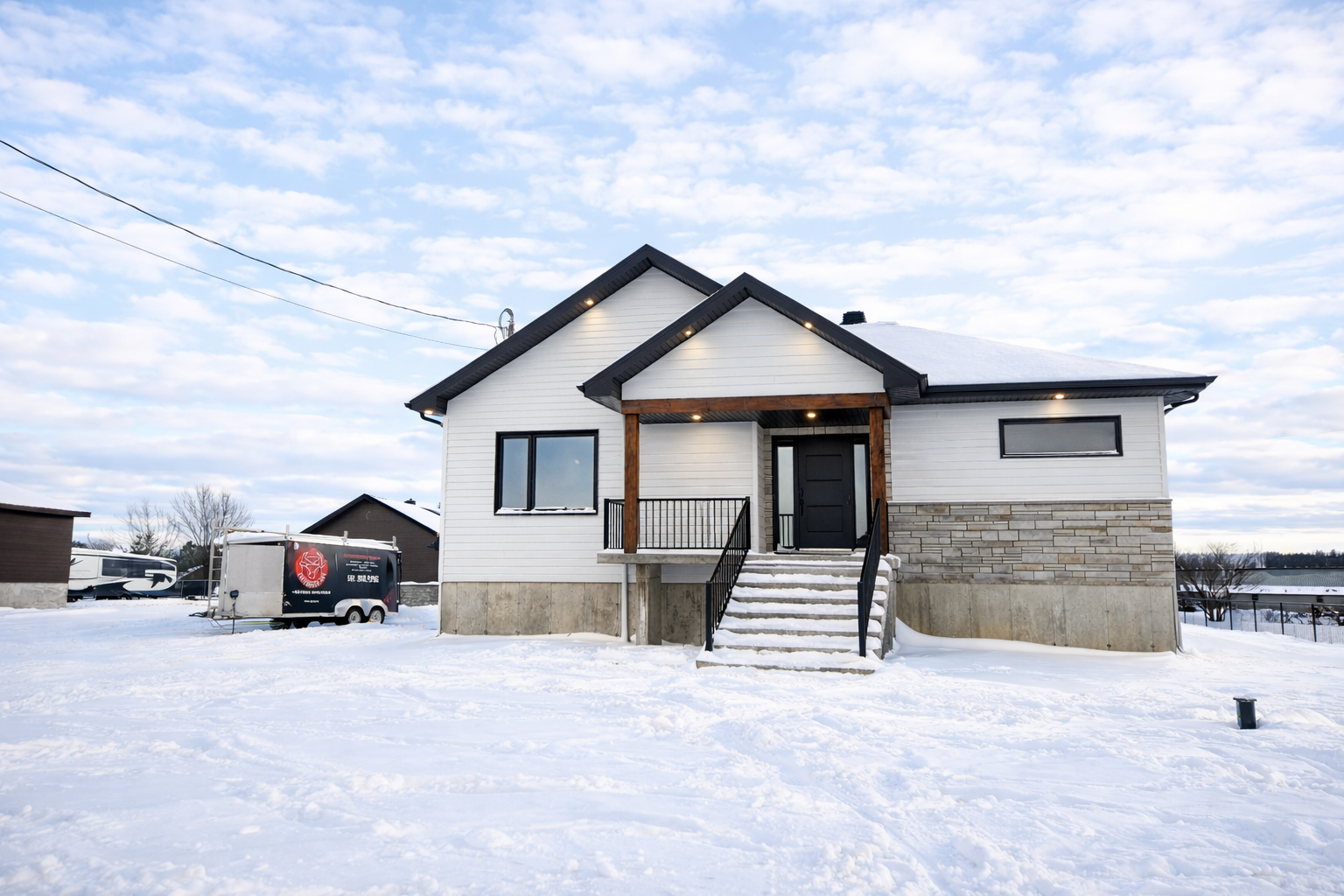 Maison blanche aux boiseries noires, dans un paysage enneigé. Marches menant à la porte d'entrée.