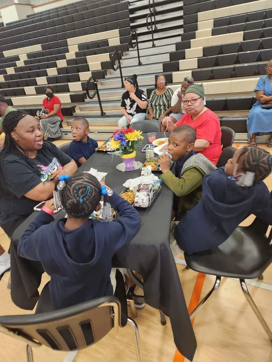 A group of people are sitting around a table in a gym
