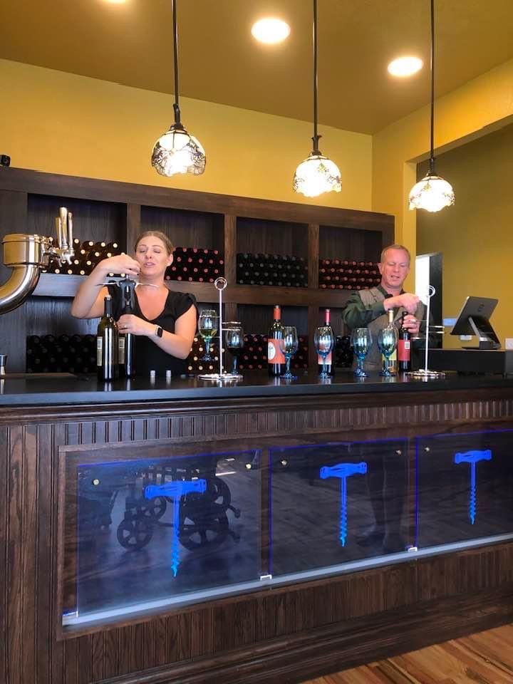 A man and a woman are standing behind a bar.