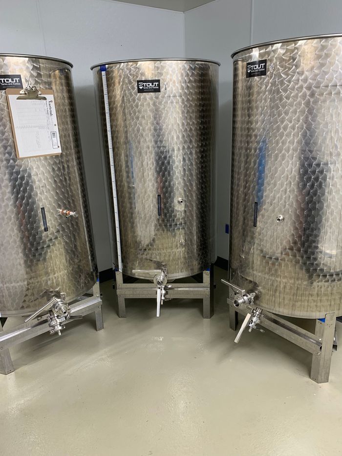 Three stainless steel tanks are sitting next to each other in a room.