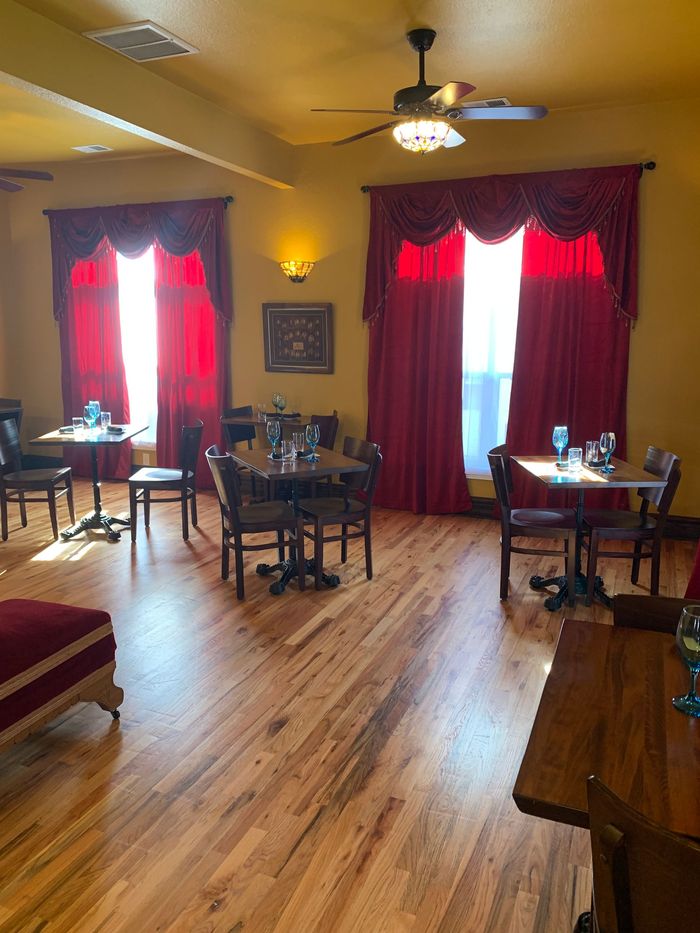 A restaurant with tables and chairs and red curtains