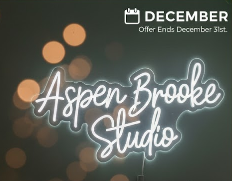 Neon sign for Aspen Brooke Studio; text glows white with a December offer ending December 31st.