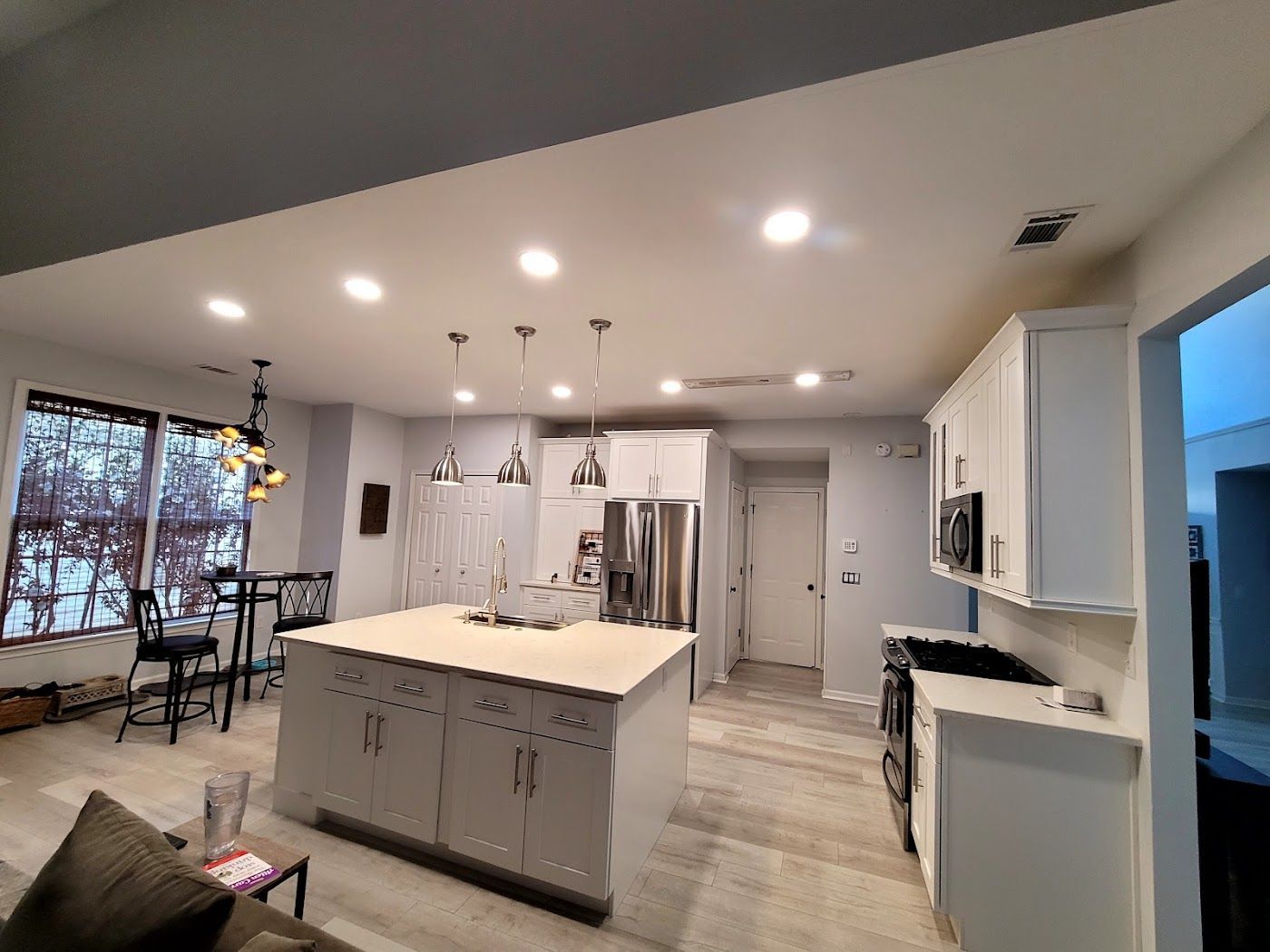 Modern kitchen with island, stainless steel appliances, and white cabinets.