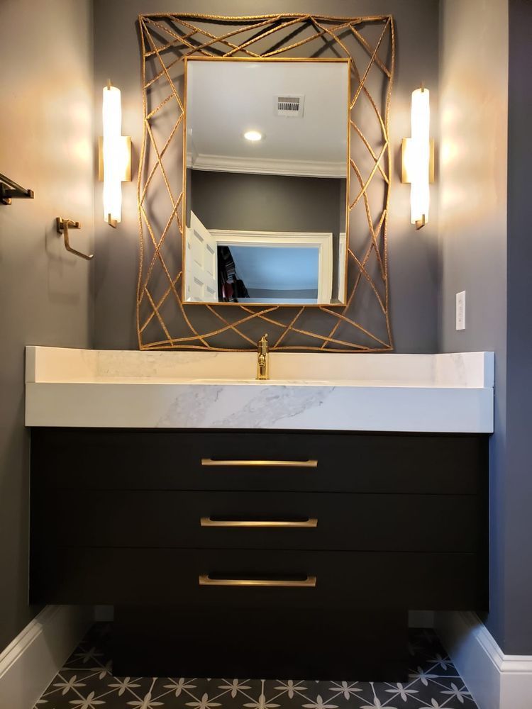 Modern bathroom vanity with a black cabinet, gold accents, and a large mirror.