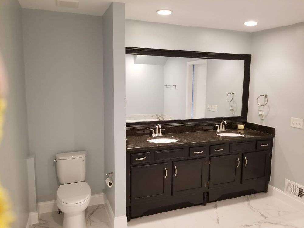 Bathroom with a dark brown vanity, double sinks, a large mirror, and a white toilet.