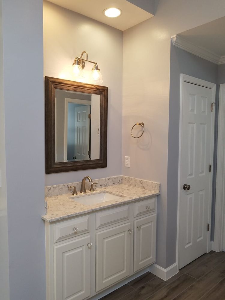 Bathroom with white vanity, framed mirror, light fixture, and a closed white door.