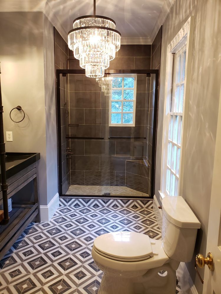 Bathroom with patterned floor, glass shower, and crystal chandelier.
