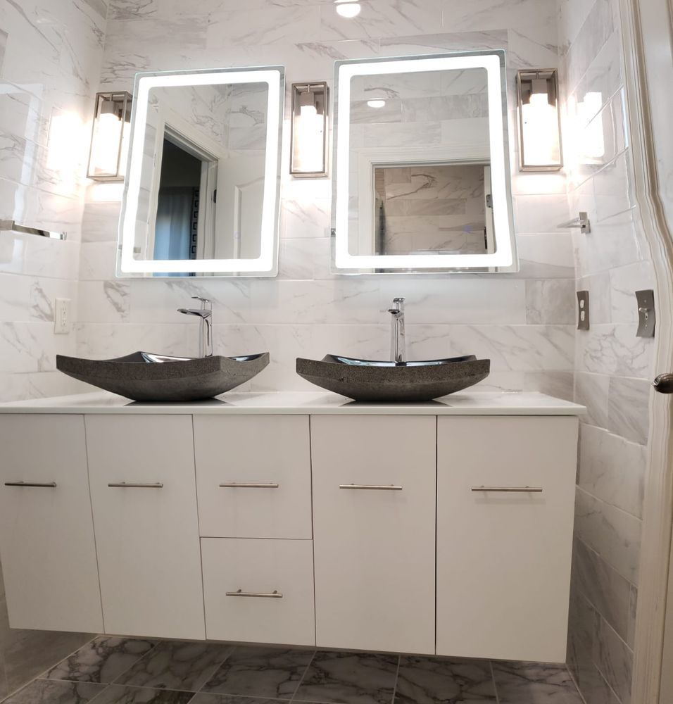 Modern bathroom with two sinks, mirrors with lights, and white cabinetry.