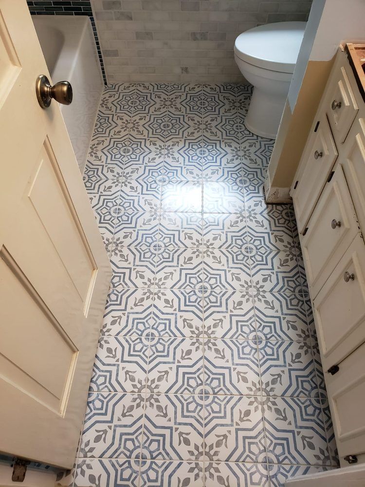 Bathroom with patterned blue and gray floor tiles, white cabinets, and a toilet.