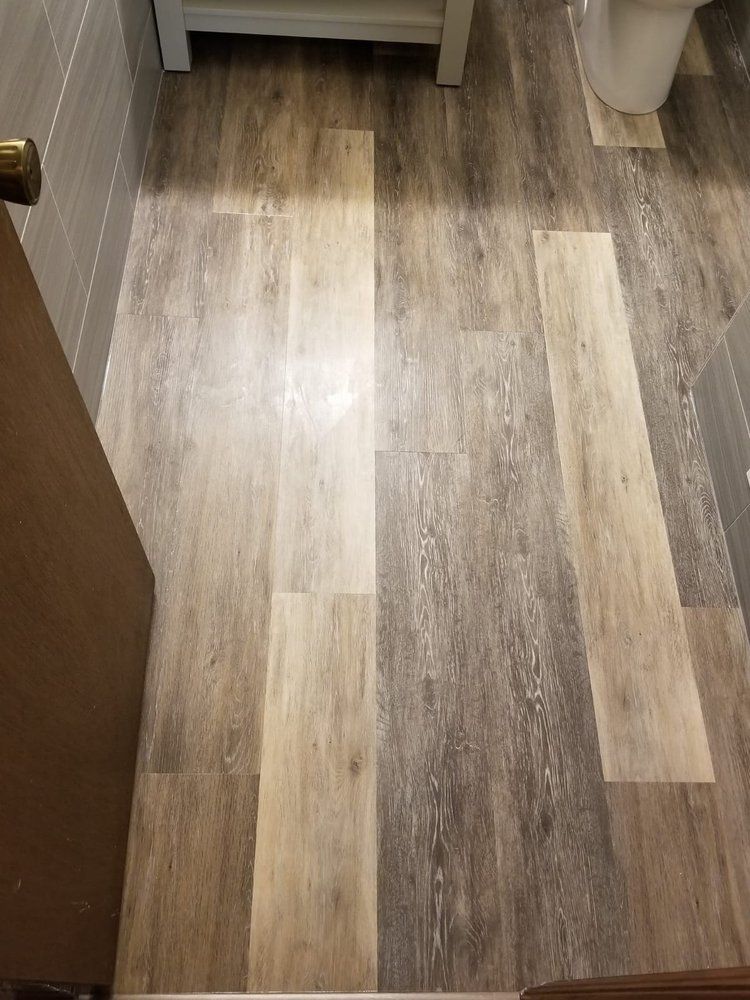Bathroom floor with vinyl plank flooring in shades of gray and beige.