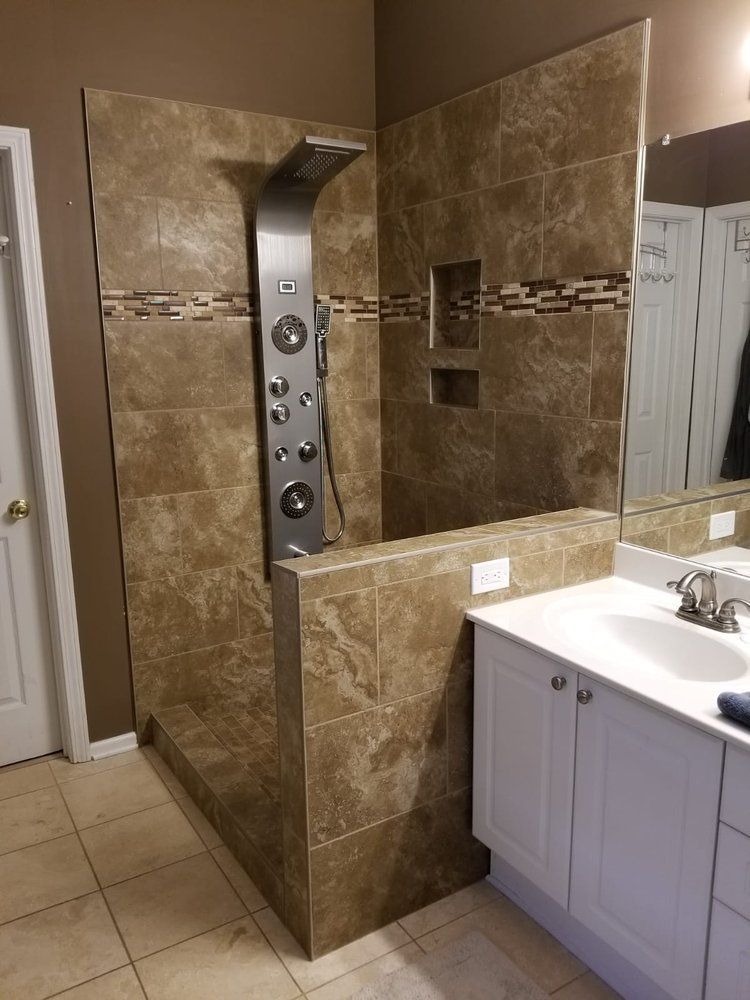 Bathroom with brown tiled shower and stainless steel shower panel. White vanity.