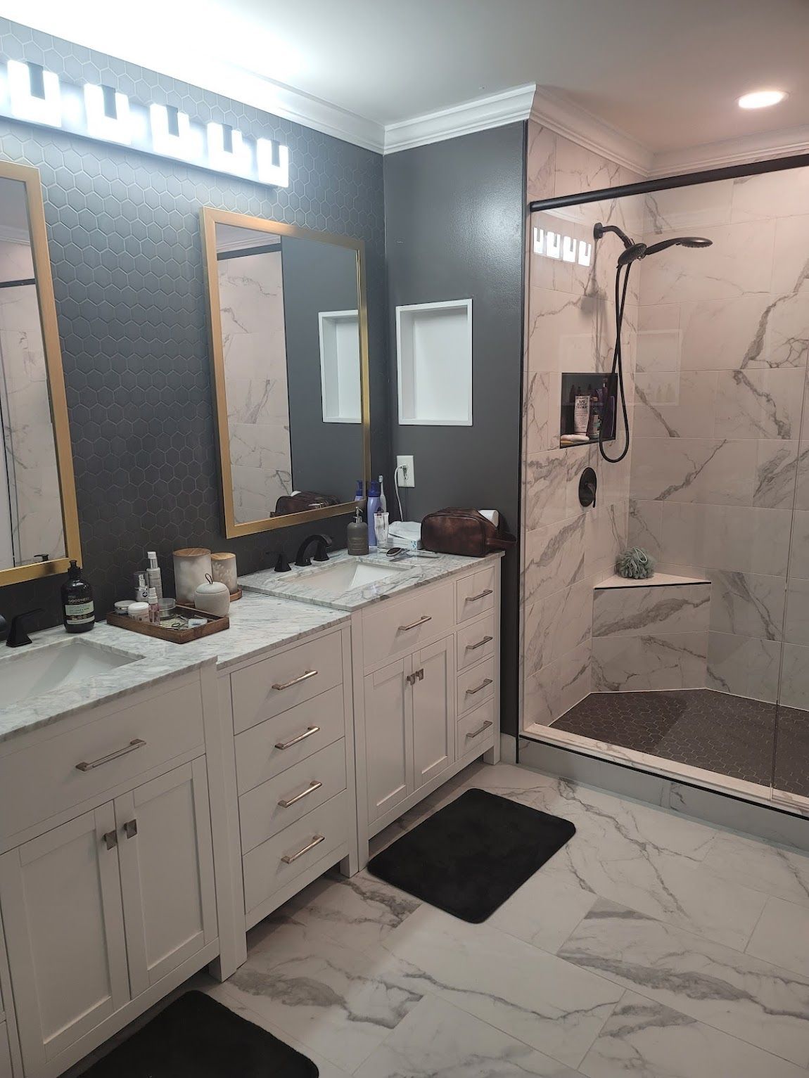 Bathroom with marble tile, white vanity, black shower fixtures, and a gray accent wall.
