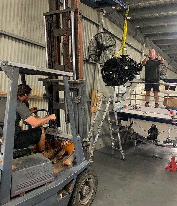 Mechanic Lifting Outboard Engine Using Fork Lifter Machine — Outboard Spare Parts In Cairns, QLD