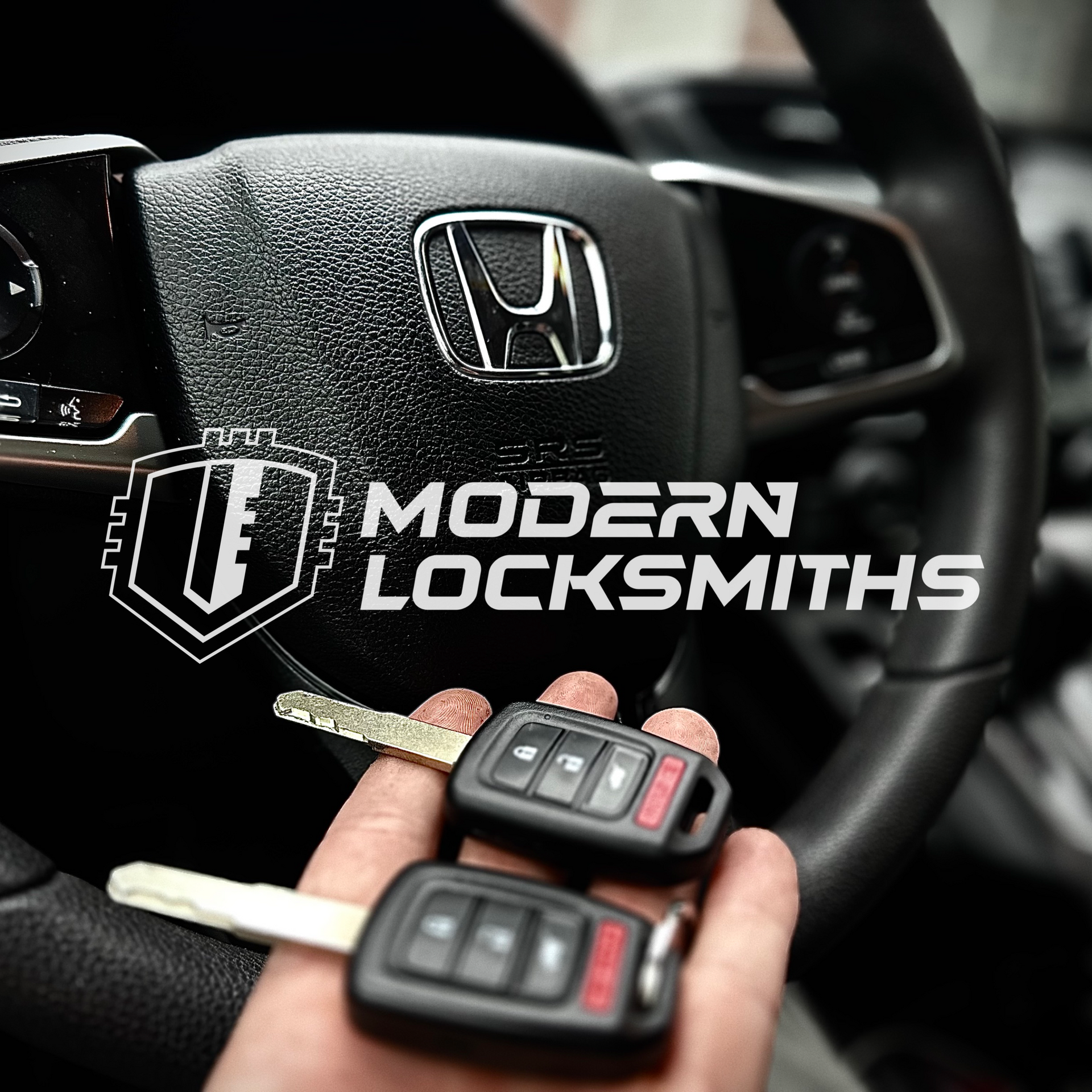 a hand holding a Honda remote key in front of a steering wheel