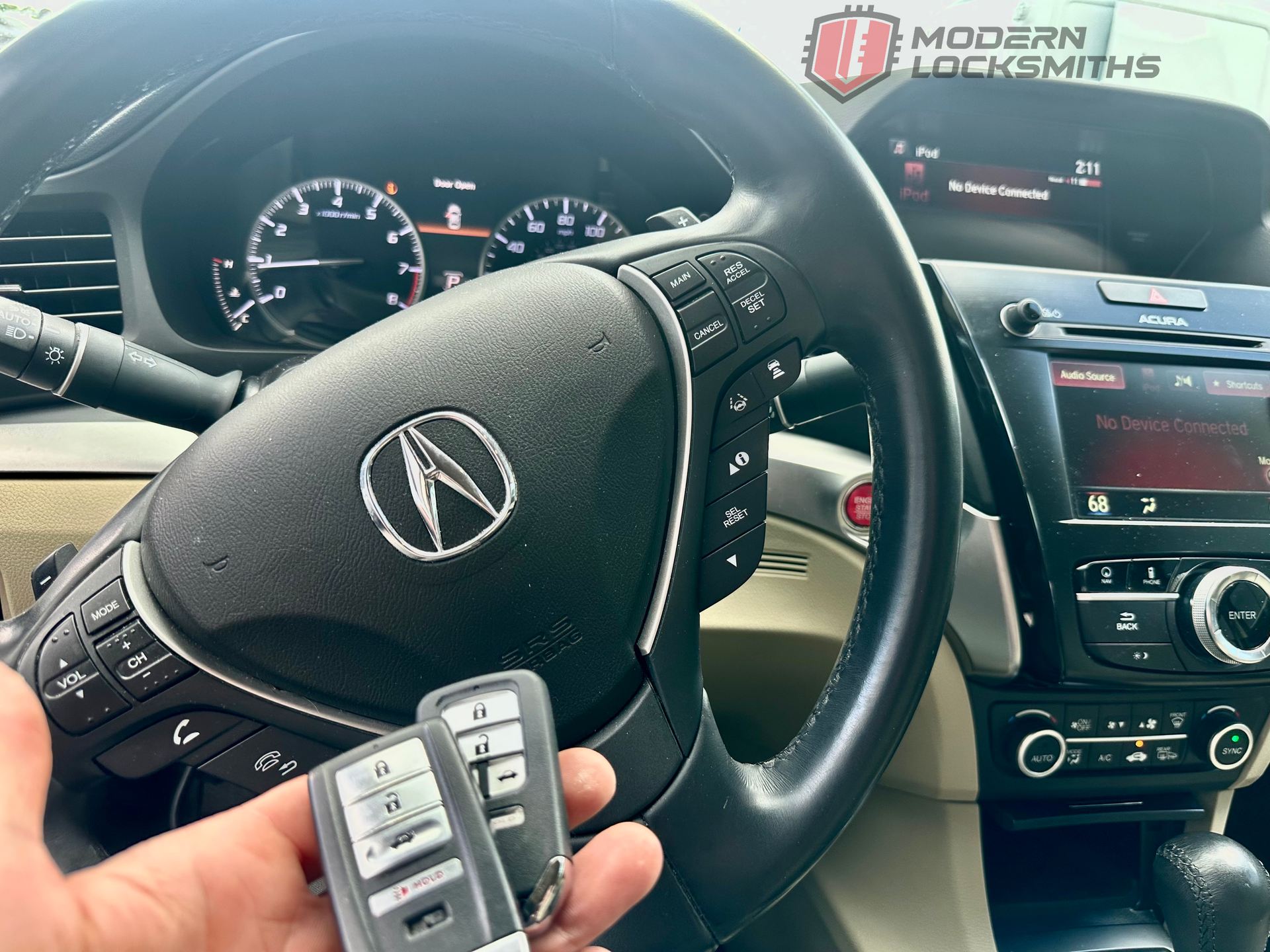 a hand holding an Acura remote key in front of a steering wheel