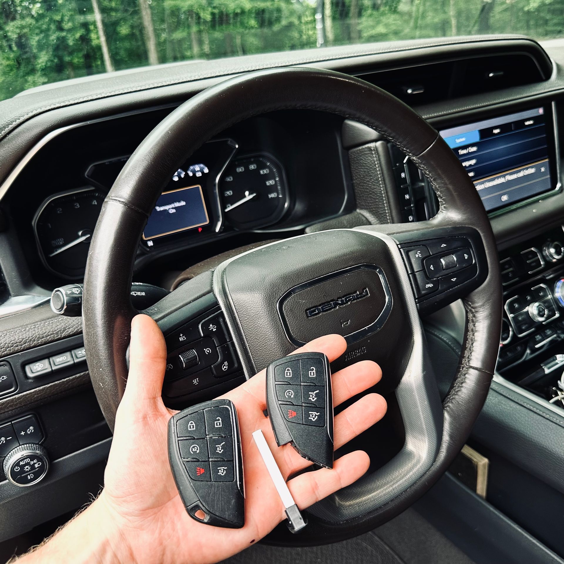 a hand holding a Chevrolet vehicle remote in front of a steering wheel