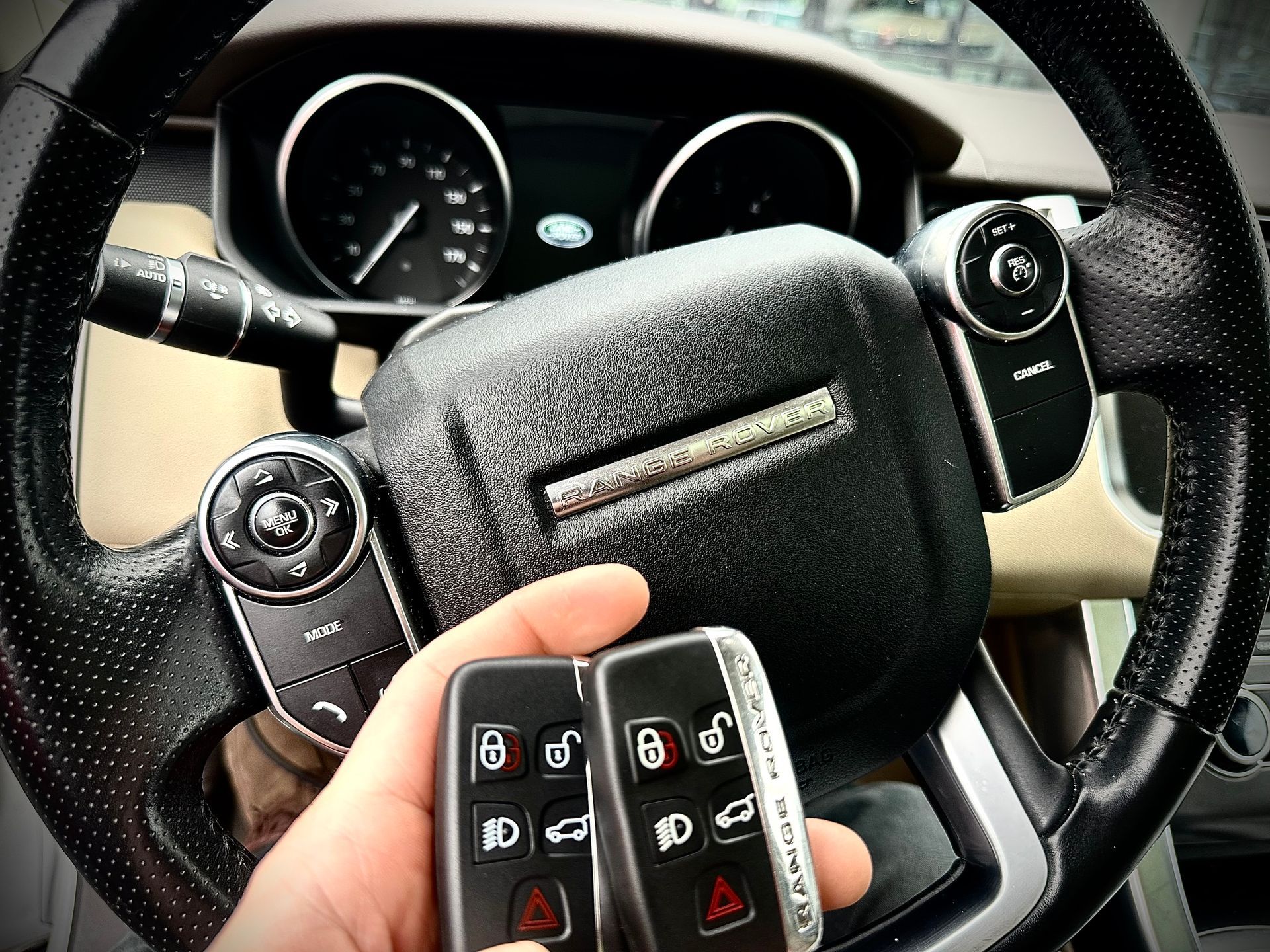 interior view of vehicle presenting a hand holding two key fobs in front of steering wheel