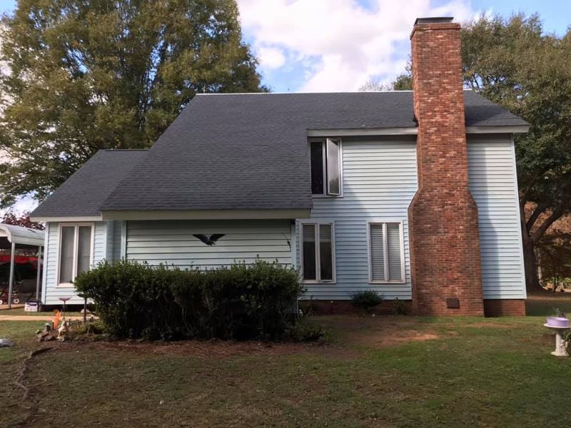 A blue house with a brick chimney on the side