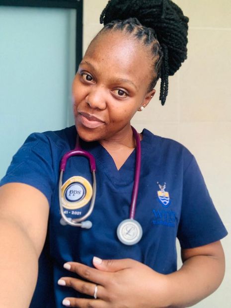 A woman wearing a scrub top and a stethoscope is taking a selfie.