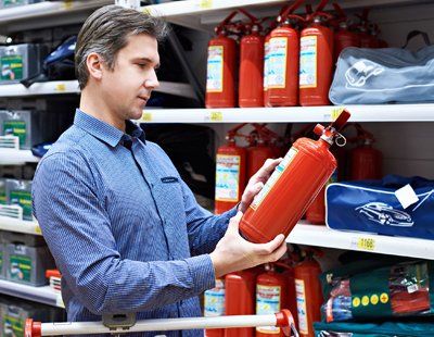 Kitchen Fire Extinguishers — Man Looking On A Fire Extinguisher In Keswick, VA