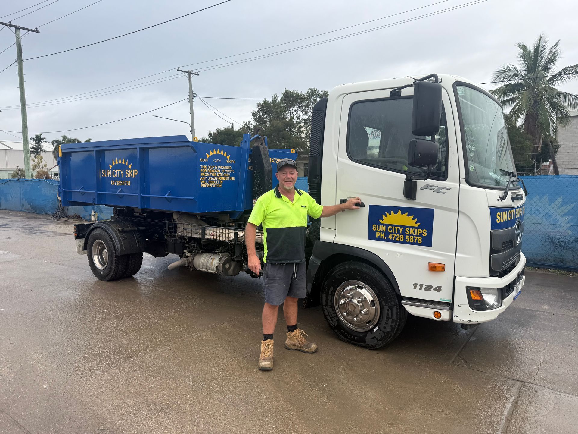 A Wooden Nightstand With A Cup Of Coffee And Books On It Next To A Bed — Sun City Skips In Bohle, QLD