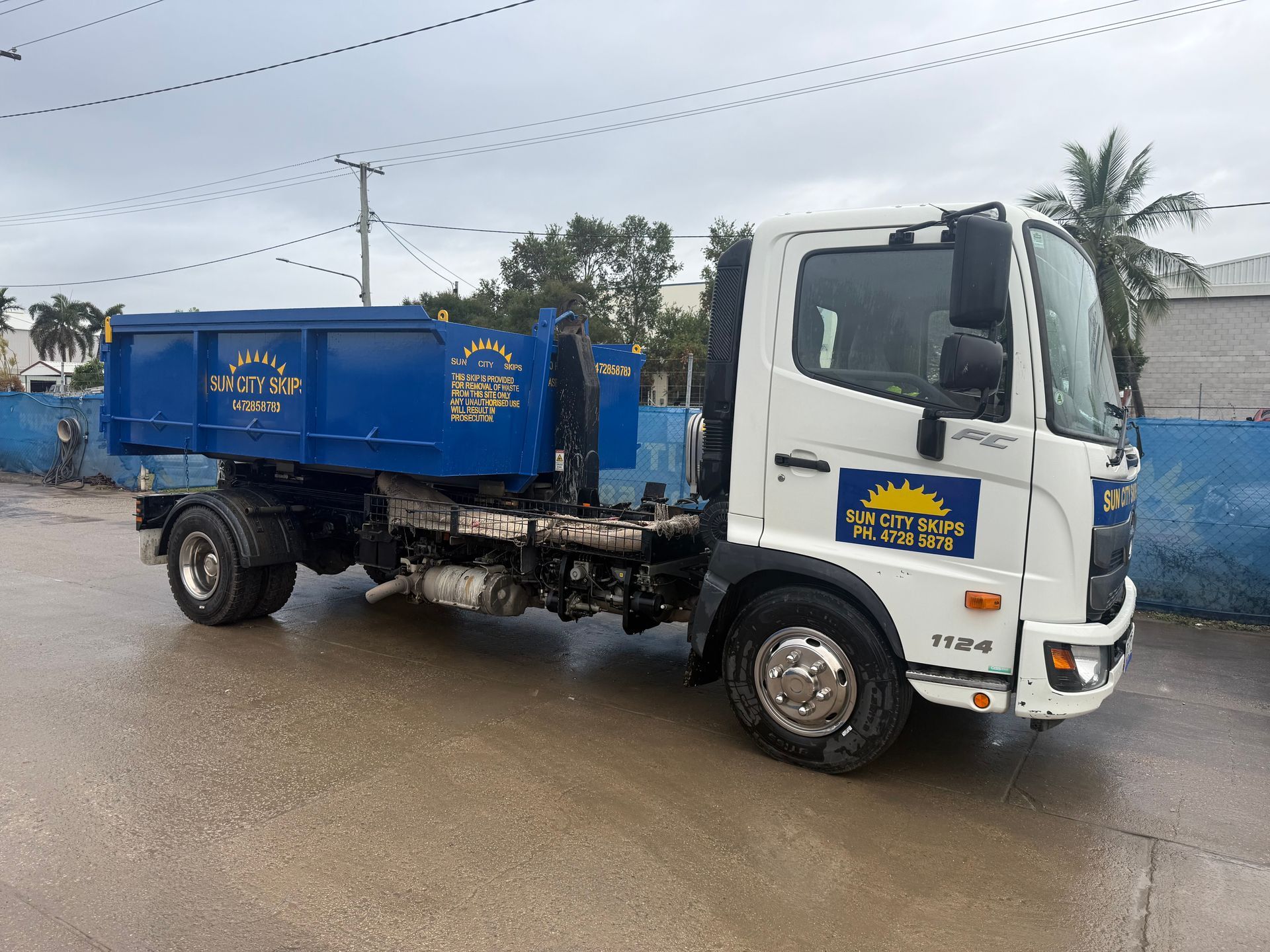 A White Van Is Parked In A Driveway Next To A Skip Bin — Sun City Skips In Bohle, QLD