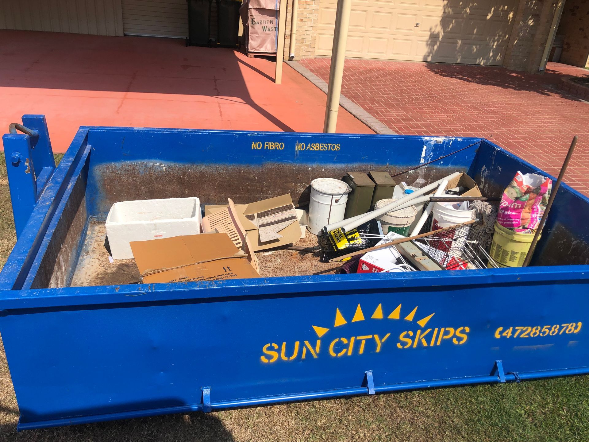 A Green Dumpster Filled With Garbage Bags And A Pile Of Trash — Sun City Skips In Bohle, QLD