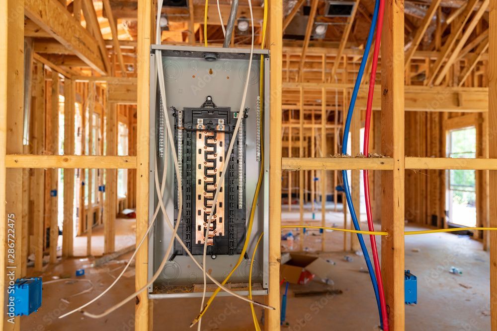 A close-up of a household electrical distribution board with multiple circuit breakers and a digital display.