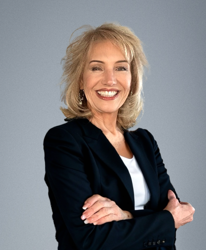 A woman in a black jacket is smiling with her arms crossed