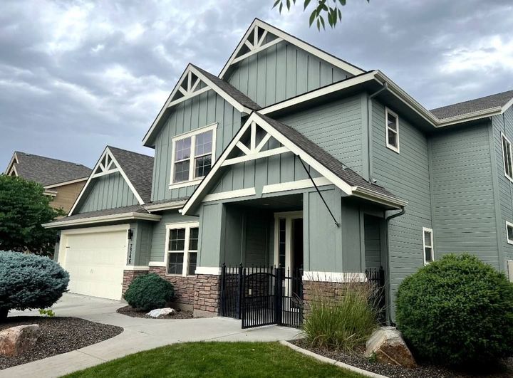 A large green house with a white trim and a gray roof.
