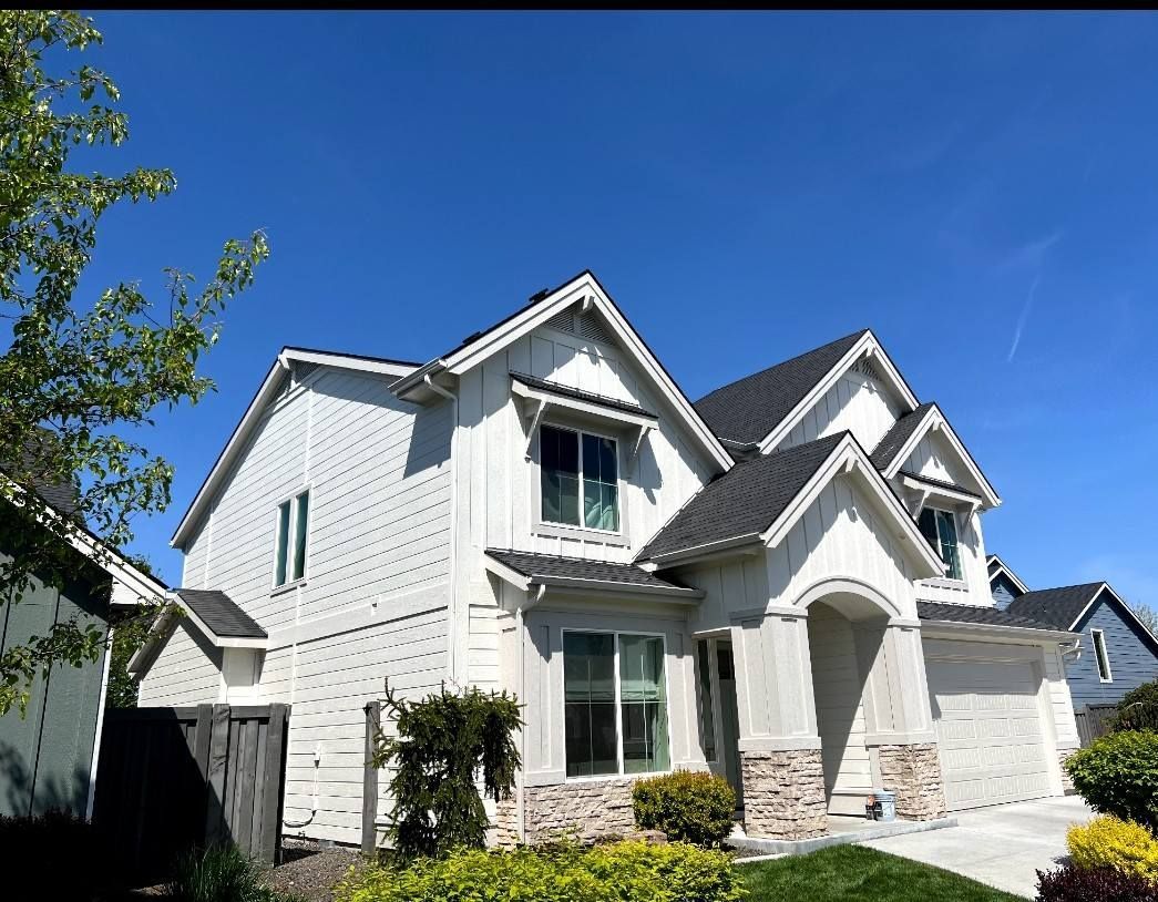 A large white house with a black roof and a blue sky in the background.