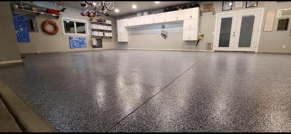 A large garage with a gray floor and white cabinets.