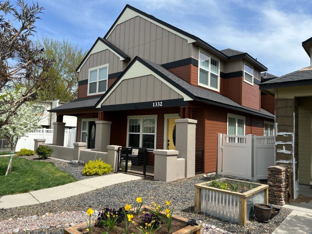 A brick house with a white fence and a planter in front of it.