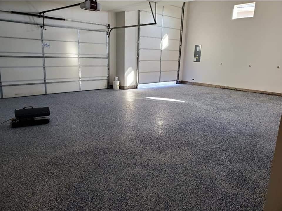 A garage with a gray floor and a white garage door.
