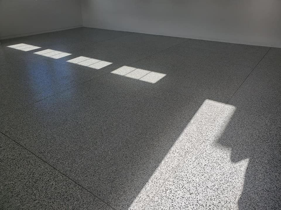 The sun is shining through the windows on the floor of a garage.