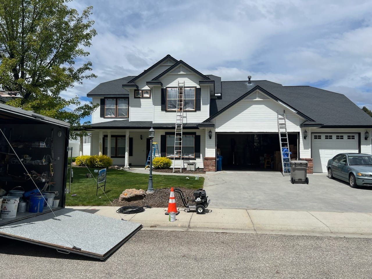 A large white house with a black roof is being painted.