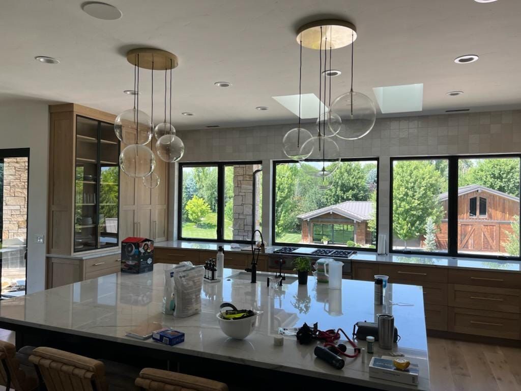 A kitchen with a large island and lots of windows.