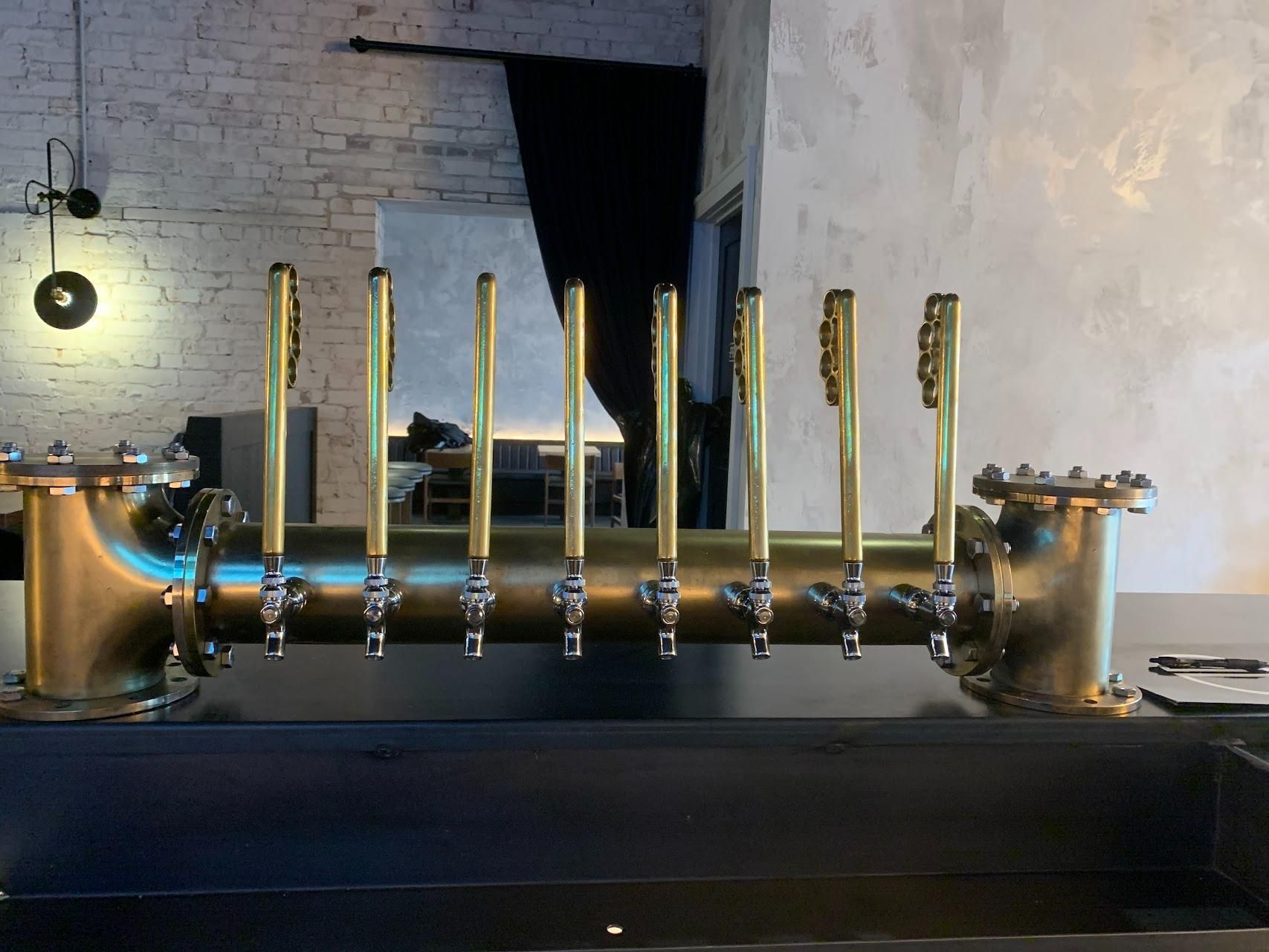 A row of brass taps are lined up on a counter.