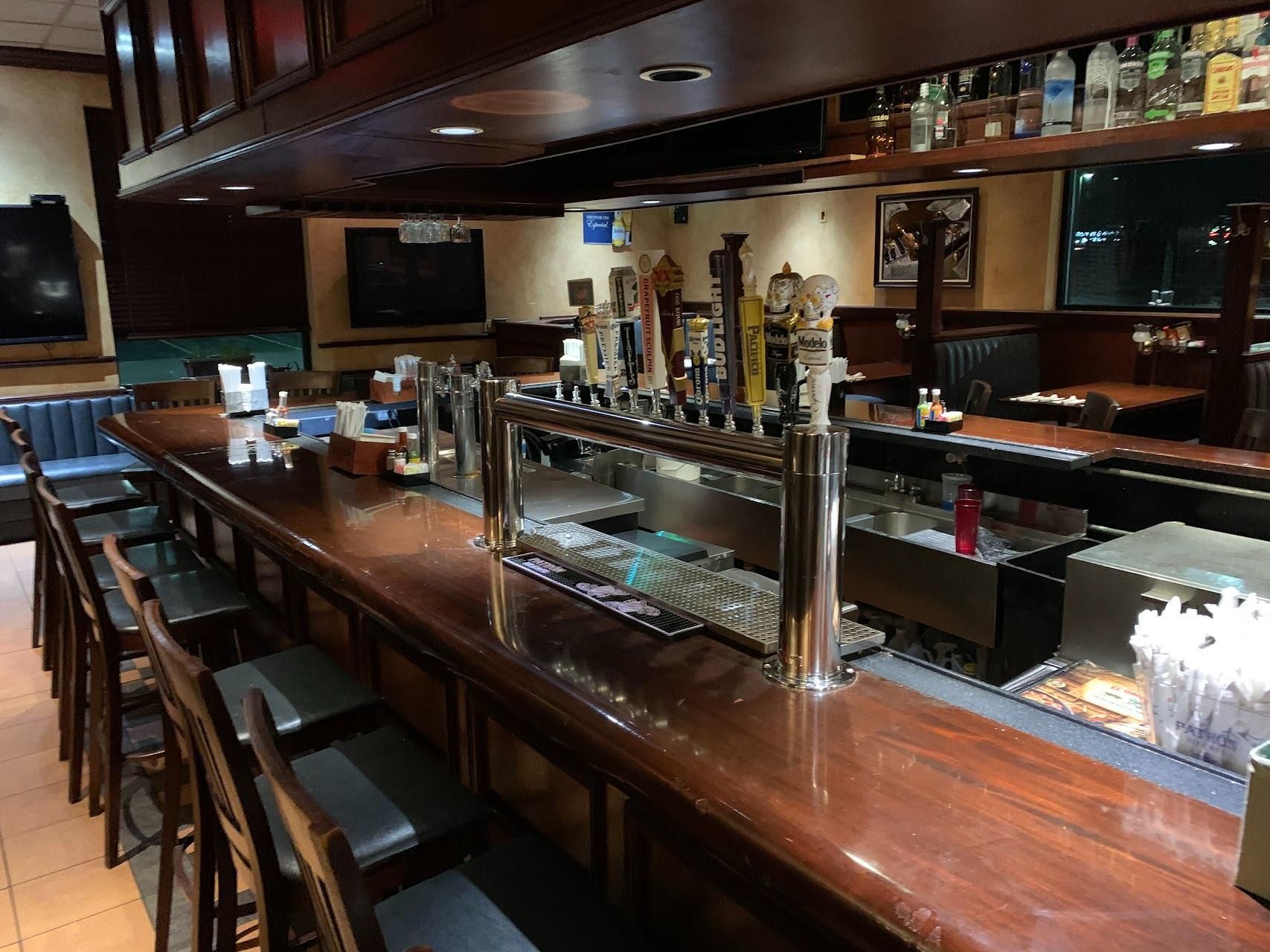A restaurant with a long wooden bar and stools