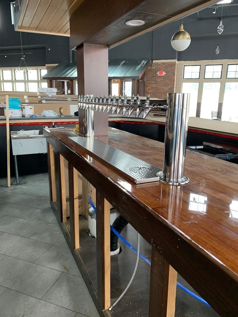 A long wooden bar in a restaurant with a stainless steel tap