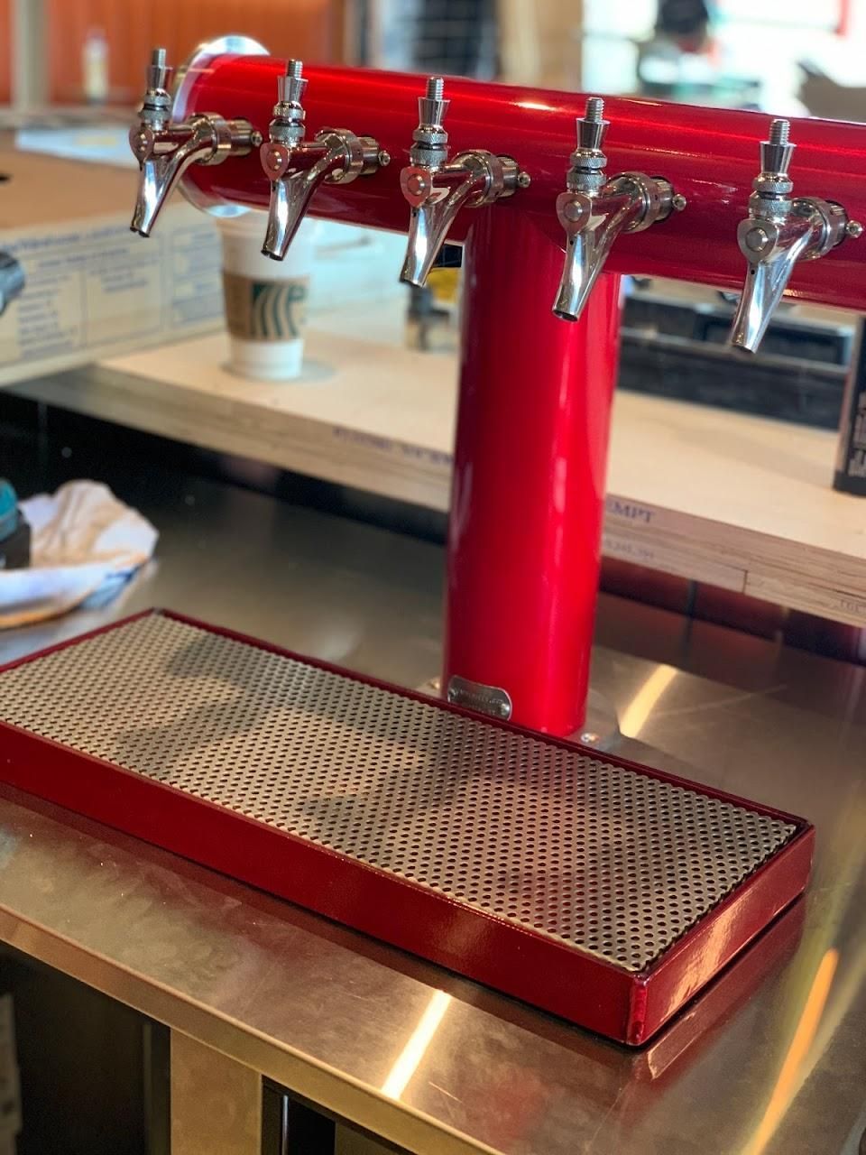 A stainless steel counter top with a red faucet on it