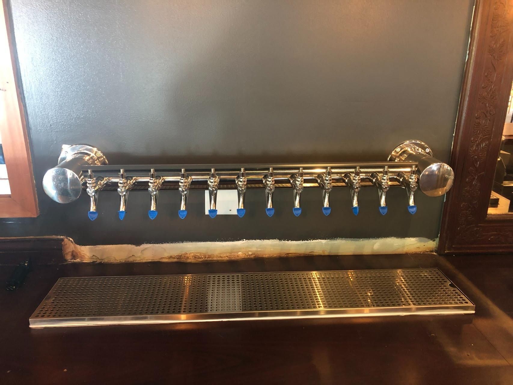 A row of faucets are hanging on a wall.