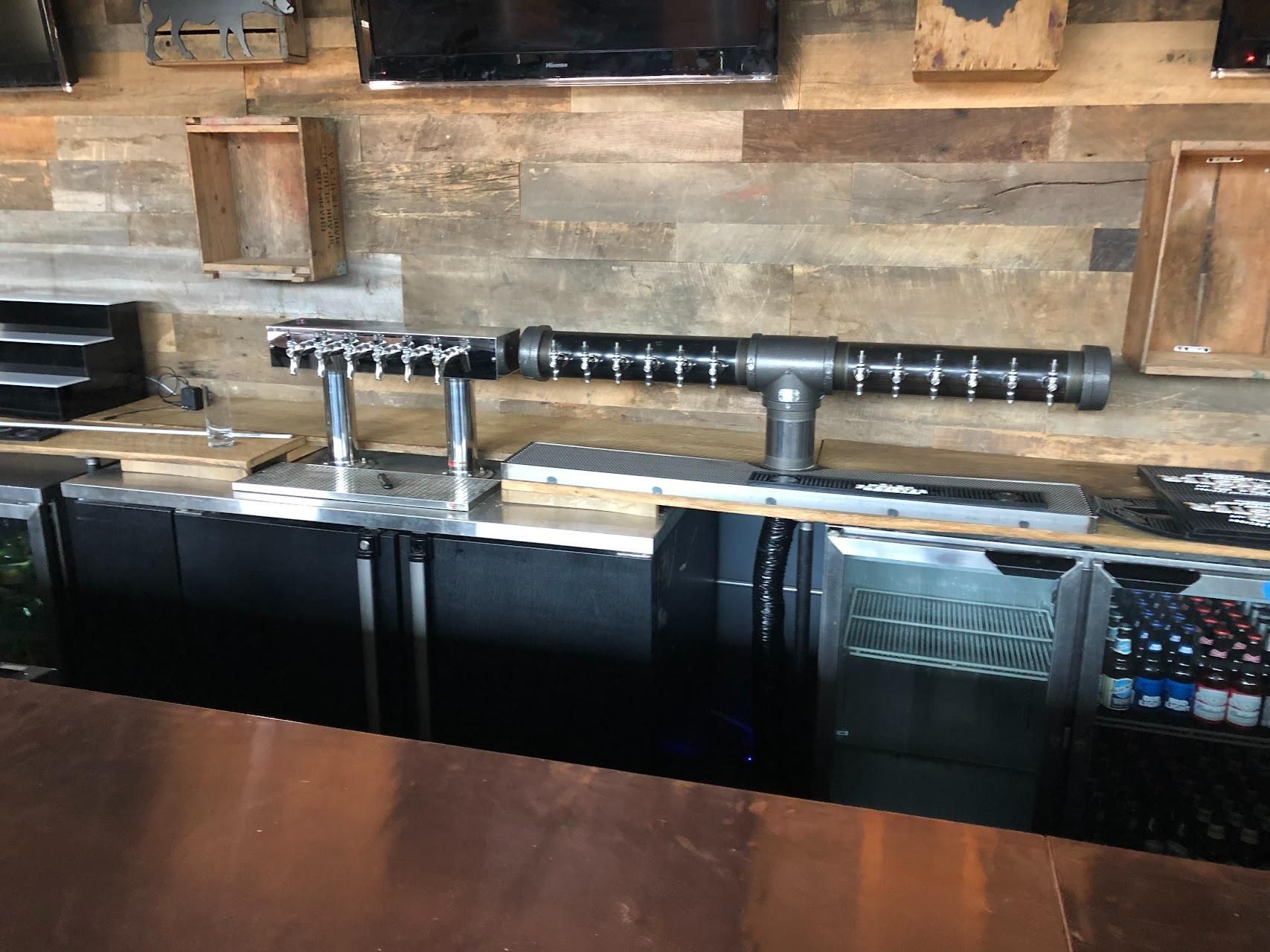A bar with a wooden wall and a metal pipe on the counter.
