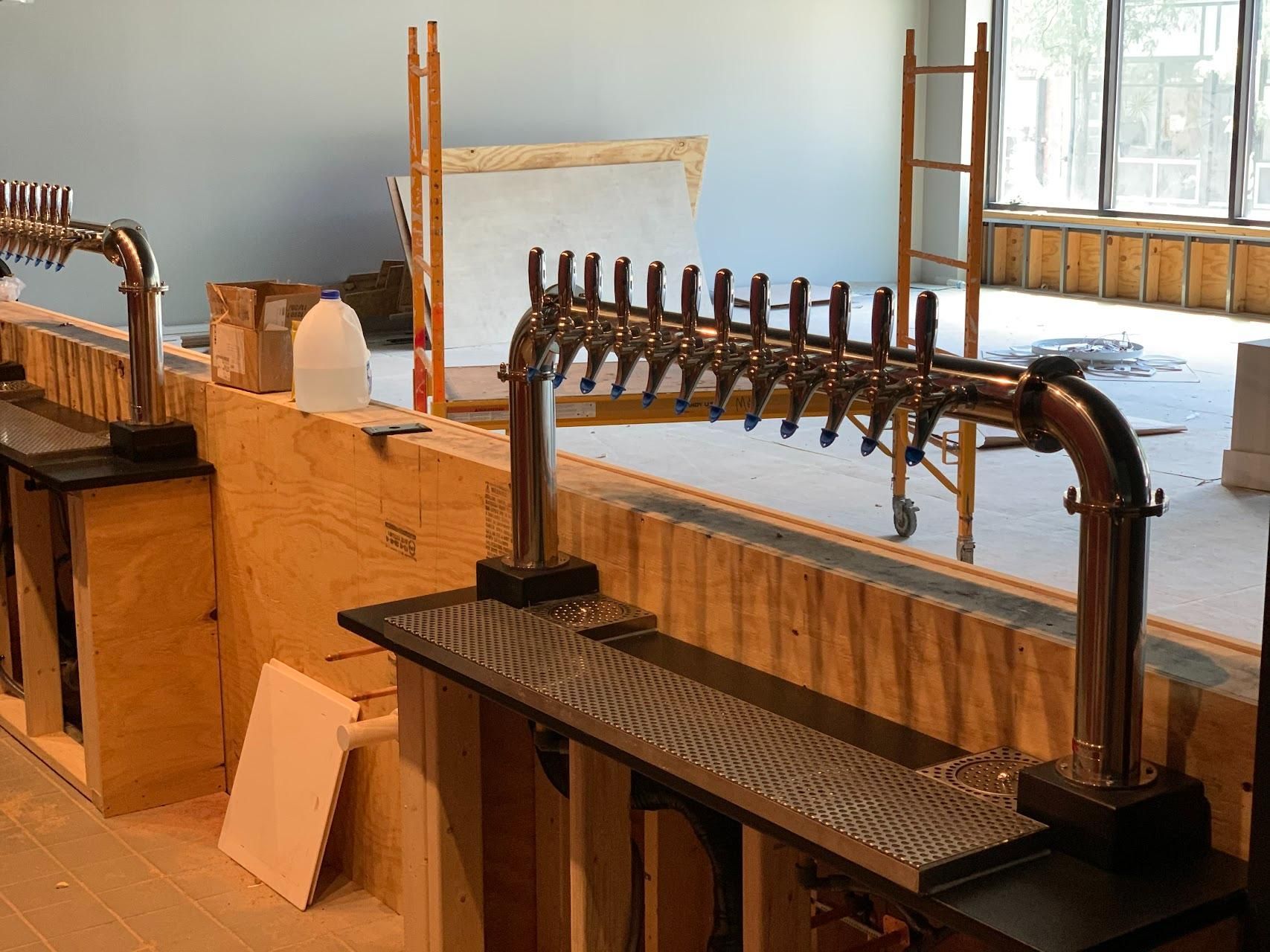 A row of beer taps are lined up in a room under construction.