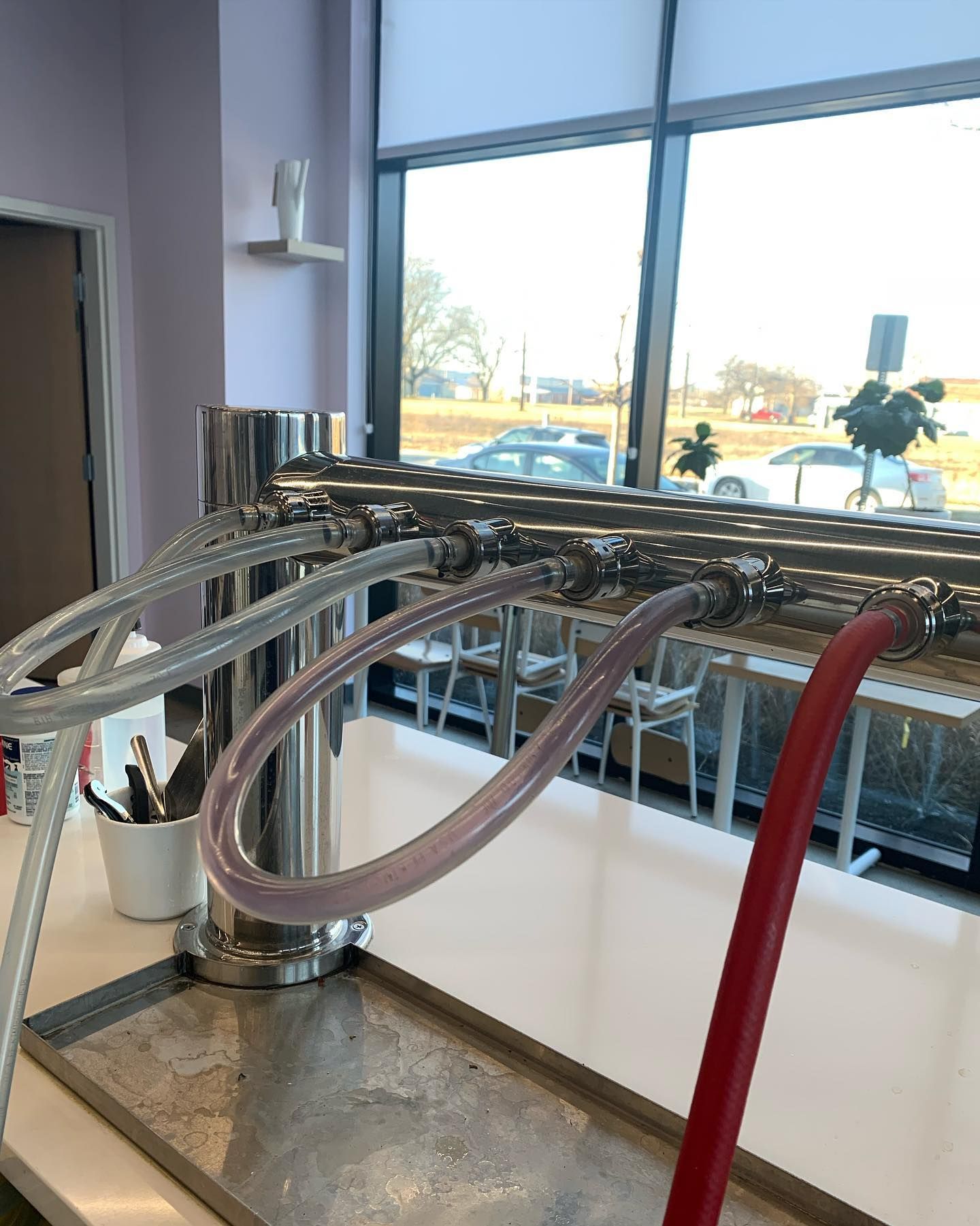 A machine with a red hose attached to it is sitting on a table in front of a window.